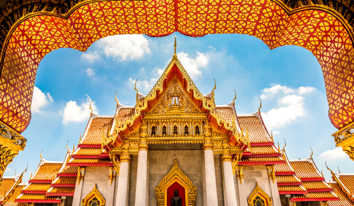 Golden Buddhist temple in Chiang Mai, Thailand with scenic mountains.